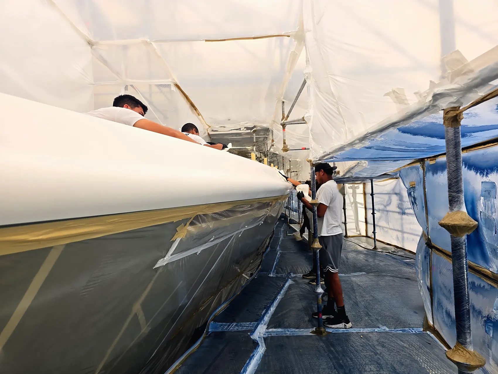 Superyacht hull under a full containment tent, freshly finished topcoat